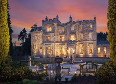 an old stone house with a fountain in front of it at Crossbasket Castle, Hotel & Restaurant in High Blantyre