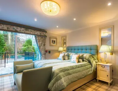 a bedroom with a bed and a large window at Crossbasket Castle, Hotel & Restaurant in High Blantyre