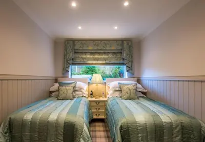 a bedroom with two beds and a window at Crossbasket Castle, Hotel & Restaurant in High Blantyre