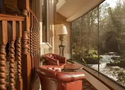 a room with two chairs and a large window at Crossbasket Castle, Hotel & Restaurant in High Blantyre