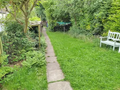 a path in the grass next to a white bench at Glasgow Hampden Garden Flat in Glasgow