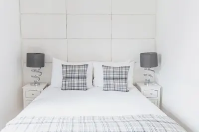 a bedroom with a white bed with two lamps at Edinburgh Castle Apartments in Edinburgh