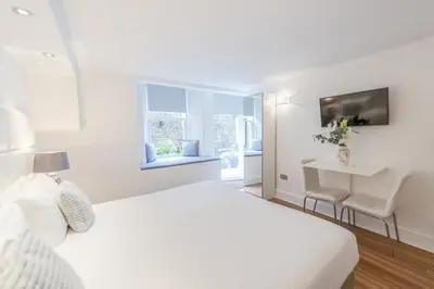 a white bedroom with a white bed and a window at Edinburgh Castle Apartments in Edinburgh