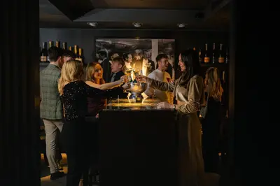 a group of people standing around a bar at Dakota Glasgow in Glasgow