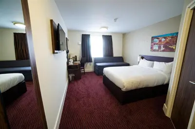 a hotel room with two beds and a couch at Red Squirrel, Stevenston by Marston's Inns in Stevenston