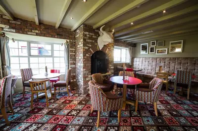 a restaurant with tables and chairs and a fireplace at Red Squirrel, Stevenston by Marston's Inns in Stevenston