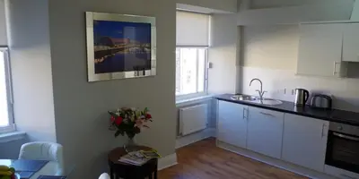 a kitchen with white cabinets and a vase of flowers on a table at Dreamhouse Apartments Glasgow St Vincent Street in Glasgow
