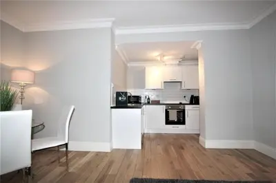 a kitchen with white cabinets and a table in a room at Dreamhouse Apartments Glasgow St Vincent Street in Glasgow