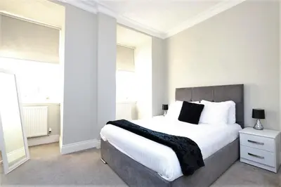a white bedroom with a large bed with white pillows at Dreamhouse Apartments Glasgow St Vincent Street in Glasgow