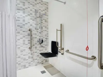 a bathroom with a shower with a black seat at Hampton by Hilton Glasgow Central in Glasgow