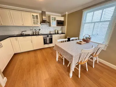 a kitchen with a table and chairs and a kitchen with white cabinets at Allt Nan Ros Apartments fort william in Onich