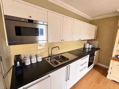 a kitchen with white cabinets and a sink and a microwave at Allt Nan Ros Apartments fort william in Onich