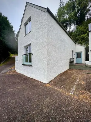 a white house with two windows and a driveway at Allt Nan Ros Apartments fort william in Onich