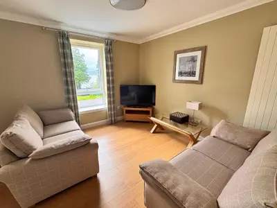 a living room with a couch and a tv at Allt Nan Ros Apartments fort william in Onich