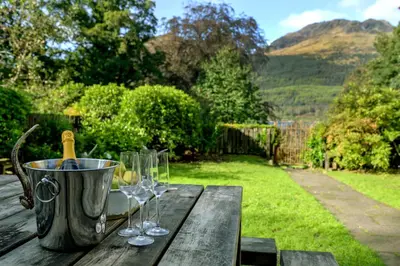 a wooden table with wine glasses and a bucket at Mansefield House in Arrochar
