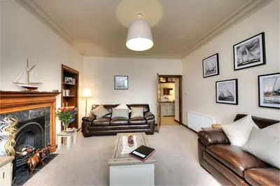 a living room with leather couches and a fireplace at Argyll Mansions in Oban