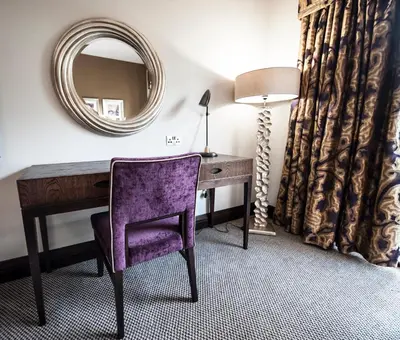 a desk with a purple chair and a mirror at Parklands Hotel & Country Club in Newton Mearns