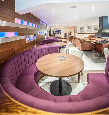 a restaurant with purple chairs and a wooden table at Parklands Hotel & Country Club in Newton Mearns