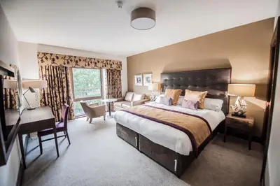 a bedroom with a large bed and a desk at Parklands Hotel & Country Club in Newton Mearns