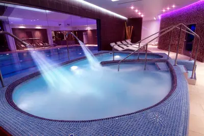a large hot tub in a hotel room with stairs at Parklands Hotel & Country Club in Newton Mearns