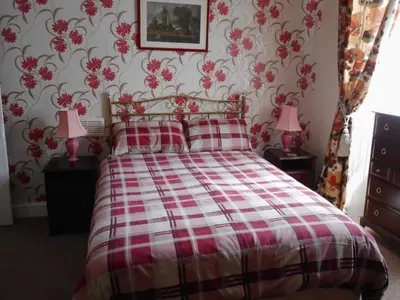 a bedroom with a red and white bed with two pink lamps at Telford Manor House in Beattock