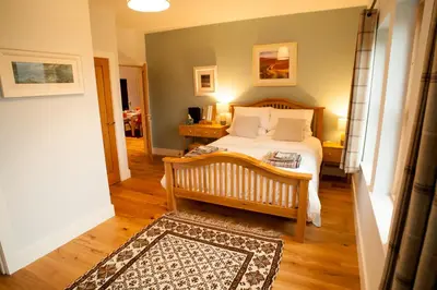 a bedroom with a bed and a wooden floor at Ceo Mara Croft b&b & 2 luxury Cabins in Taynuilt