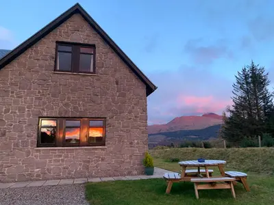 a stone house with a picnic table in front of it at Ceo Mara Croft b&b & 2 luxury Cabins in Taynuilt