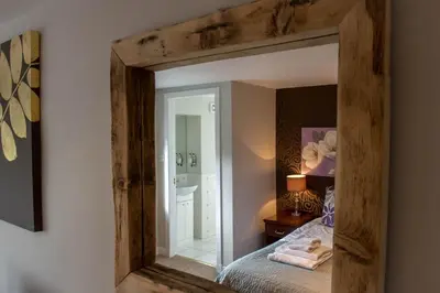 a mirror reflecting a bedroom with a bed and a bathroom at The Inn at Kippen in Kippen