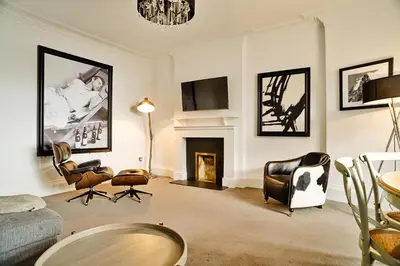 a living room with a couch and chairs and a fireplace at JOIVY Luxury Flats on George Street in Edinburgh