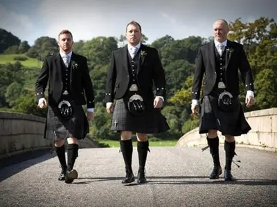 three men in kilts walking on a bridge at The Ken Bridge Hotel & Campsite in New Galloway