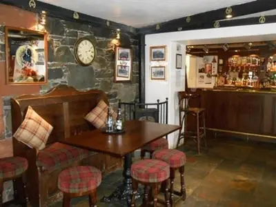 a bar with a table and a clock on a wall at The Ken Bridge Hotel & Campsite in New Galloway