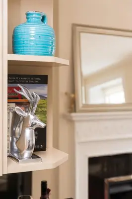 a book shelf with a blue vase and a mirror at Luxury New Town 1 Bed Apartment in Edinburgh