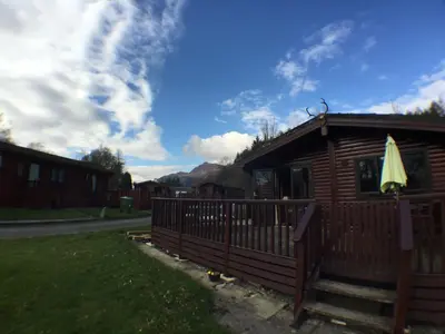 a wooden cabin with a fence and an umbrella at Lochlomondlodge22 in Rowardennan