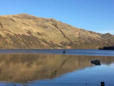 a body of water with a mountain in the background at Lochlomondlodge22 in Rowardennan