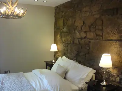 a bedroom with a stone wall and a bed with pillows at Riggend Farm Accomodation in Airdrie