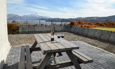 a wooden picnic table with two glasses of wine at Tigh Grianach in Connel