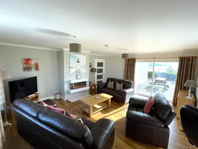 a living room with two leather couches and a fireplace at Tigh Grianach in Connel