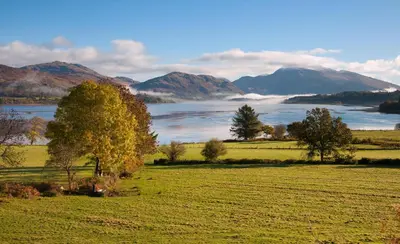 a field with a view of a lake and mountains at Tigh Grianach in Connel