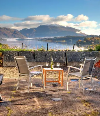 two chairs and a table with a bottle of wine at Tigh Grianach in Connel