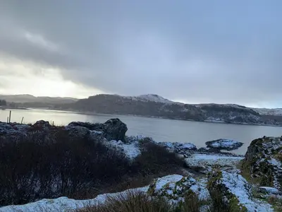 a body of water with snow on the rocks at Tigh Beg Croft in Lerags