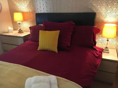 a bed with red pillows and two lamps on tables at The Guest Wing in Rothesay