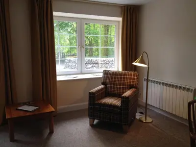 a living room with a chair and a window at Hearthstanes Steading in Polmood