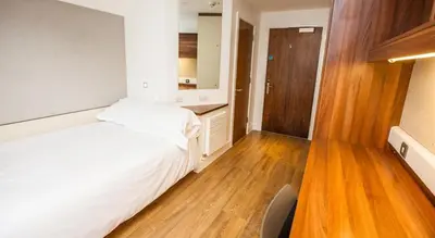 a bedroom with a white bed and a wooden floor at Juniper Court in Stirling