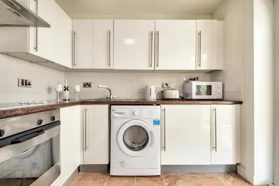 a kitchen with white cabinets and a washer and dryer at No.17 Serviced Apartment in Glasgow
