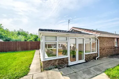 a small house with a conservatory on a lawn at No.17 Serviced Apartment in Glasgow