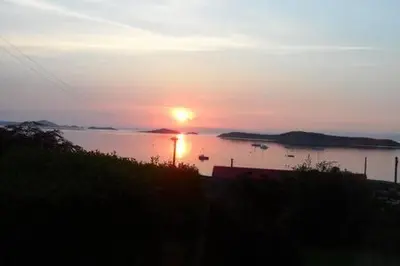 a sunset over a body of water with boats in it at Braeside Craighouse Jura in Craighouse