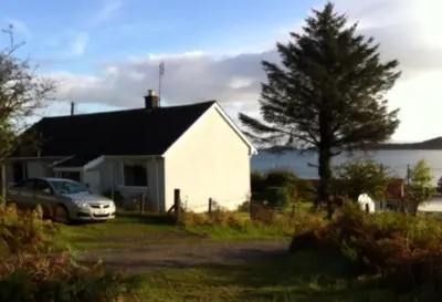 a white house with a car parked in front of it at Braeside Craighouse Jura in Craighouse