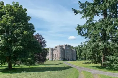 an old mansion in a field with trees at Gardener's Cottage in Crieff