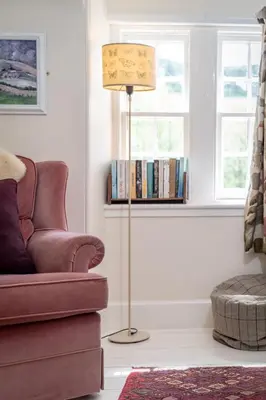 a living room with a floor lamp and a couch at Gardener's Cottage in Crieff