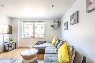 a living room with a gray couch and yellow pillows at Cosy Apartment in Quiet City-Centre with Car Park in Glasgow